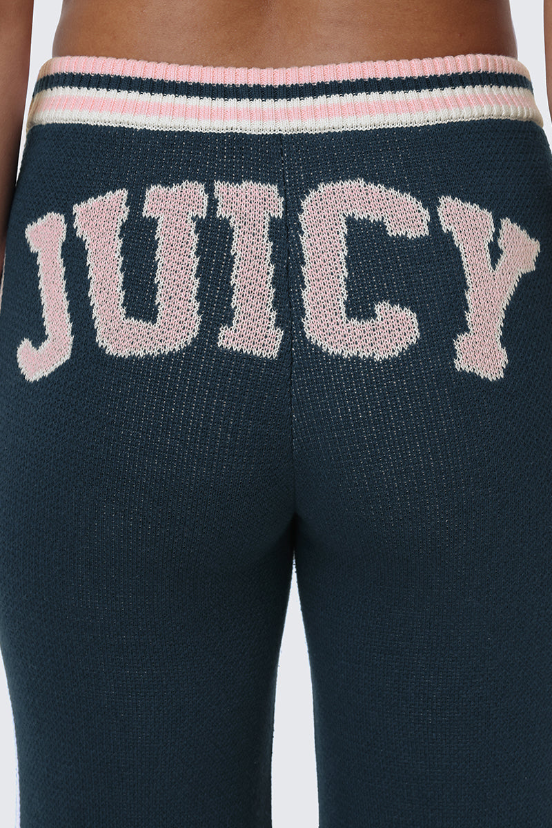 Close-up of the back of dark blue Collegiate Knit Wide Leg Pants featuring the word JUICY stitched in large, light pink letters across the upper back waistband, highlighting bold varsity-style logo detailing.