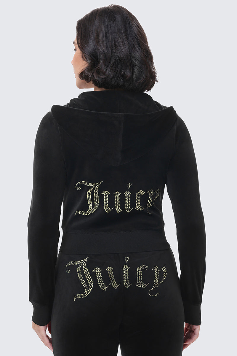 A person wears a black OG Big Bling Ribbon Hoodie and matching pants, both featuring the word Juicy in rhinestones on the back and the lower portion of the pants.