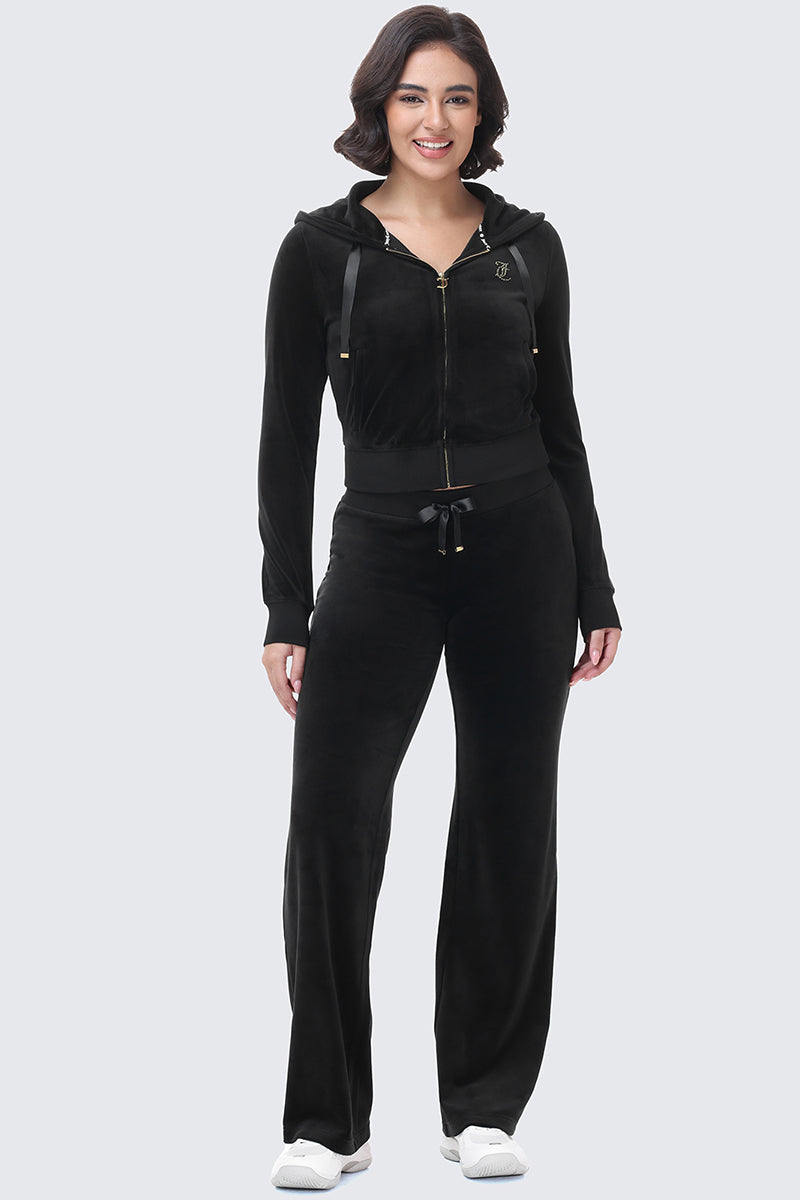 A woman wearing a black velour OG Big Bling Ribbon Hoodie with satin ribbon ties, paired with matching velour pants.
