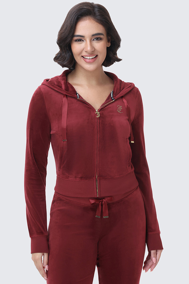 A woman wearing a dark red OG Big Bling Ribbon Hoodie featuring a fitted silhouette, gold zipper pull, and ribbon ties on the hood.
