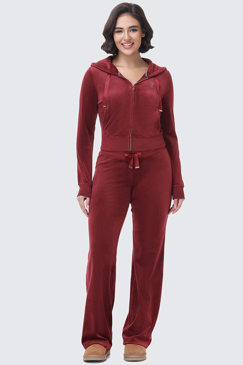 A woman wearing a fitted dark red OG Big Bling Ribbon Hoodie and matching track pants.
