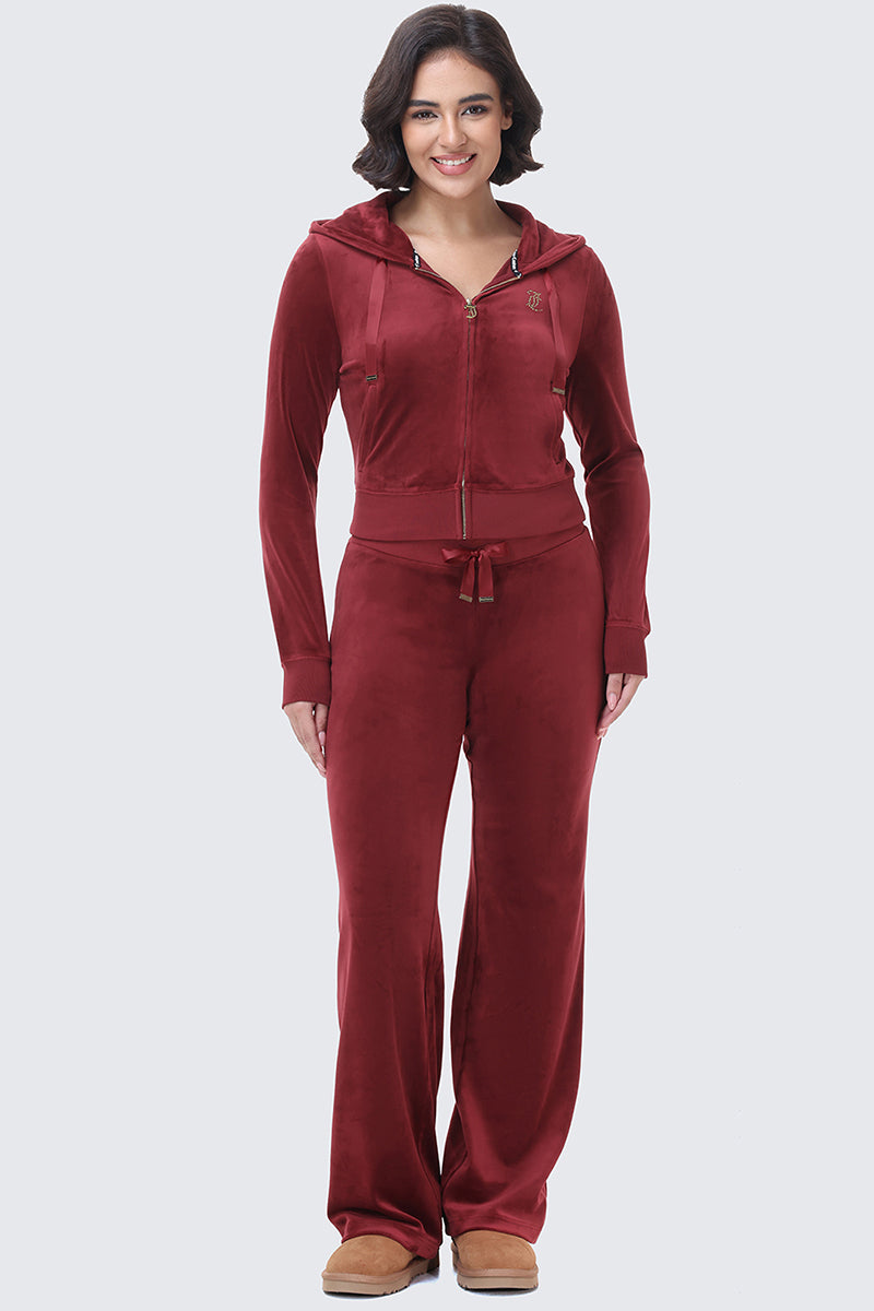 A woman wears a matching dark red hooded jacket and OG Big Bling Ribbon Track Pants, which are loose-fitting with ribbon details.