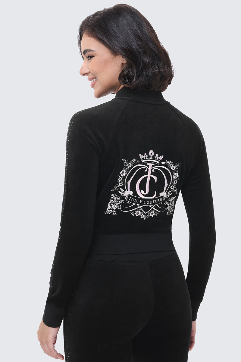 A person seen from behind wears a black, cotton velour Scottie Crown Cotton Velour Jacket featuring a silver crown and heart-shaped emblem on the back.