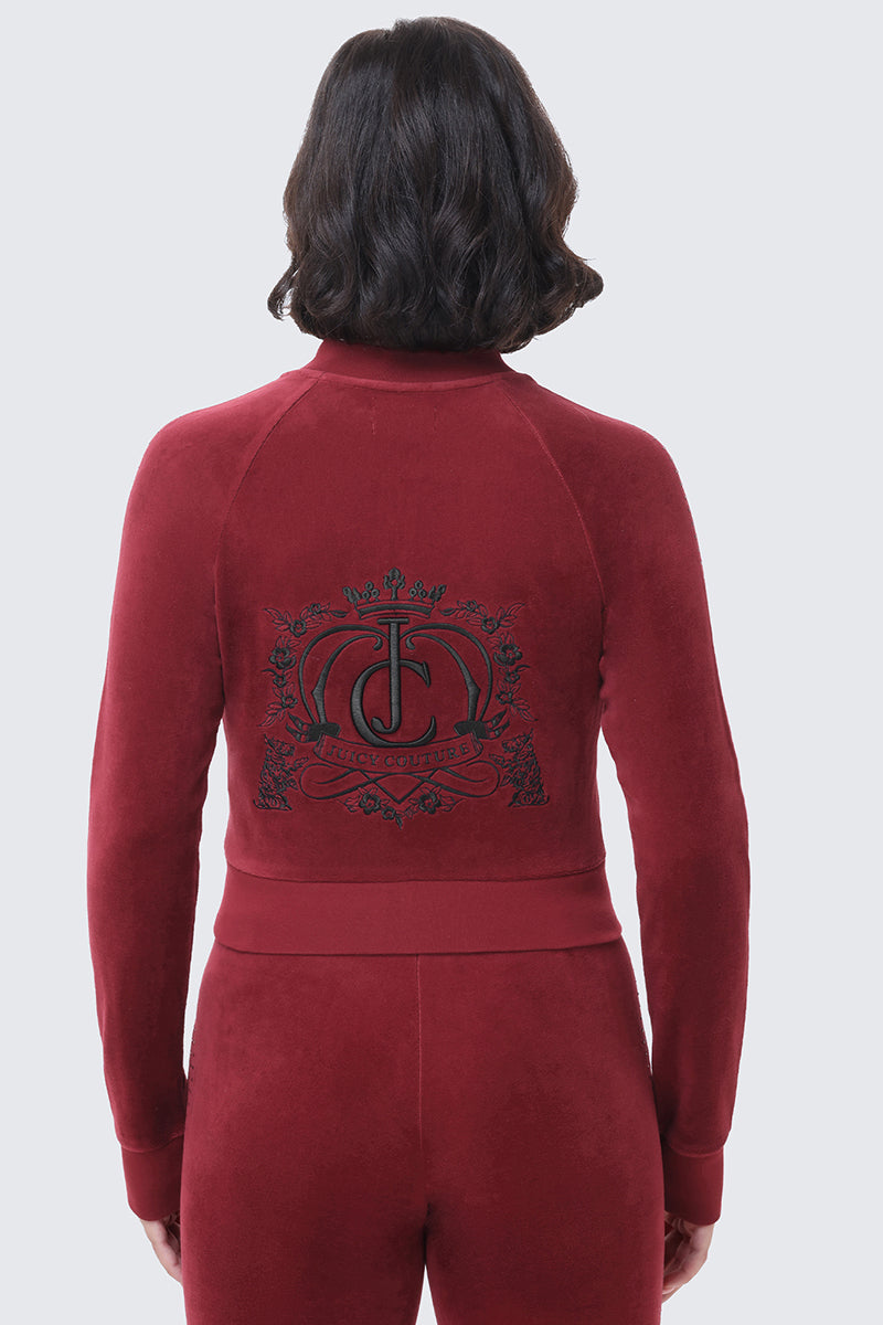 Back view of a person wearing a dark red Scottie Crown Cotton Velour Jacket featuring a black embroidered crest logo on the back.