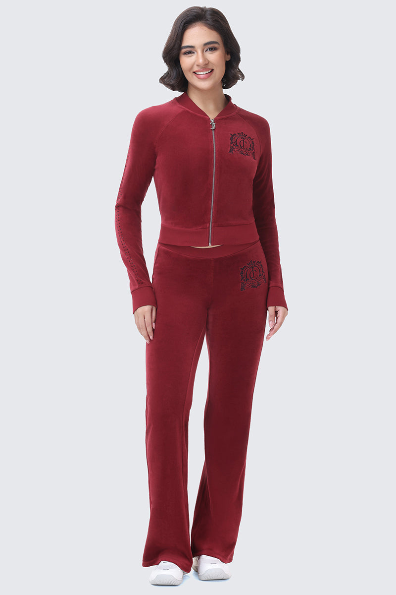A woman wears a deep red Scottie Crown Cotton Velour Jacket and matching wide-leg track pants, both featuring a black crown emblem.