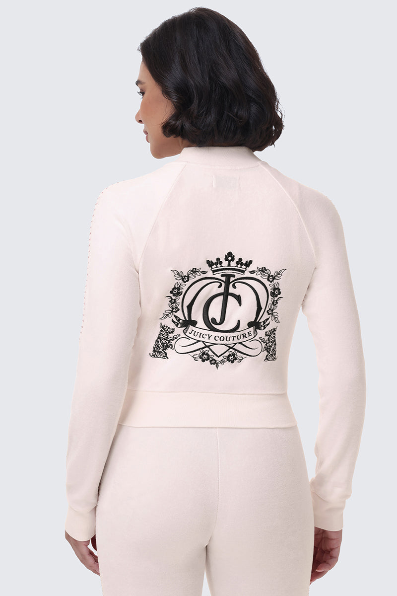 A back view of a person wearing the cream-colored Scottie Crown Cotton Velour Jacket, featuring a large black graphic of a crown and floral emblem on the back.