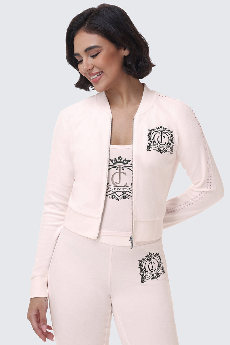 A person wearing a pale pink Scottie Crown Cotton Velour Jacket over a matching tank top, both featuring a black crown and shield graphic.