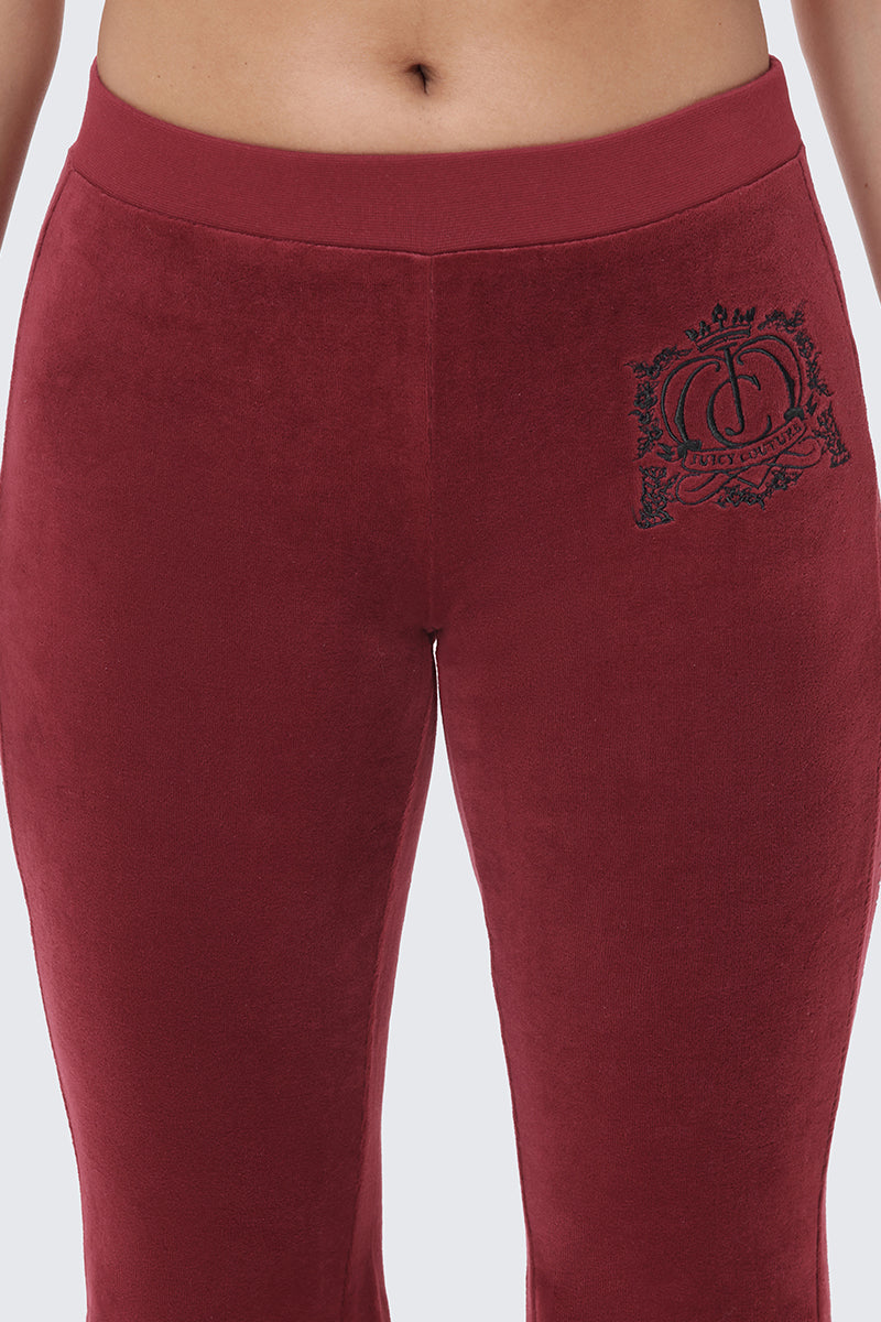 Close-up of maroon Scottie Crown Cotton Velour Track Pants with a dark embroidered crest logo on the right hip.