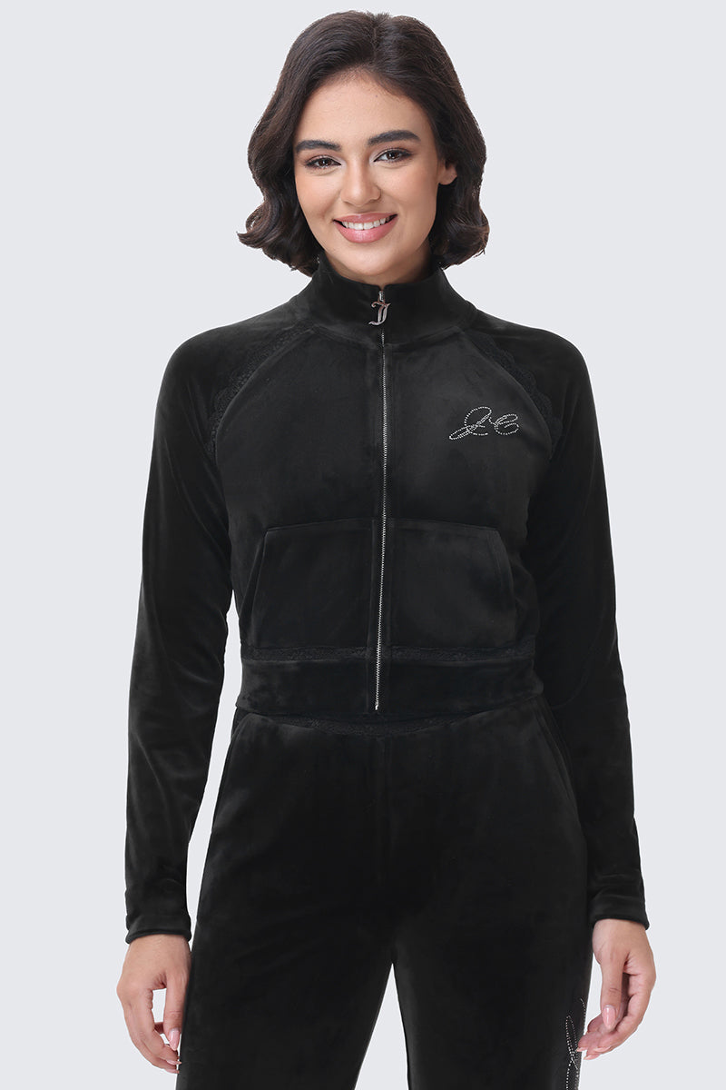 A person wears a Small Bling Velour Jacket, a Y2K-inspired black velour bomber jacket with a rhinestone detail on the chest.