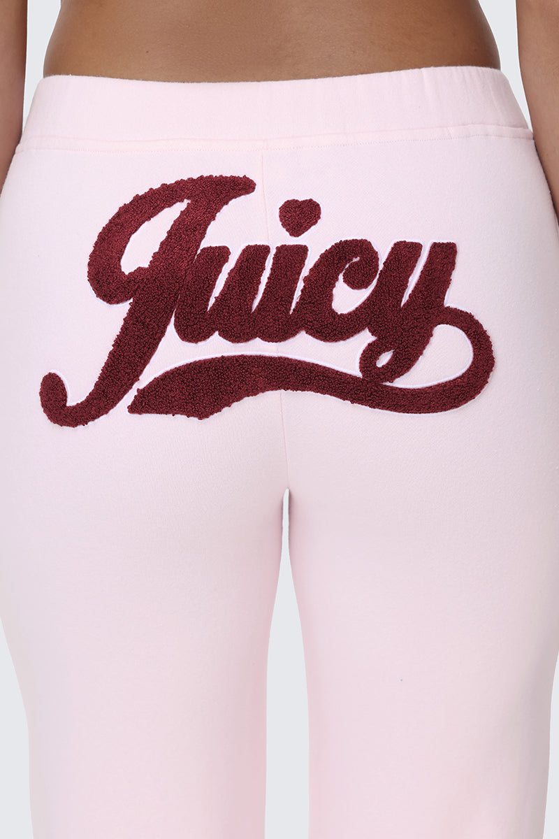 Close-up of the back of the Embroidered Knit Bubble Leg Pants in pink, featuring "Juicy" embroidered in large, dark red letters across the seat.