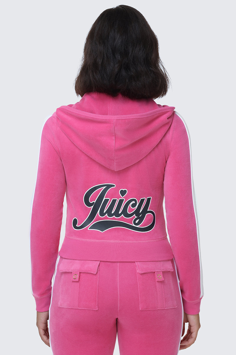 A person is seen from behind wearing the Cotton Velour Hoodie in bright pink. The hoodie features a hood and showcases Juicy’s signature script logo across the back in bold black and white lettering, complete with a small heart above the "i," highlighting the hoodie’s sporty, vibrant style.