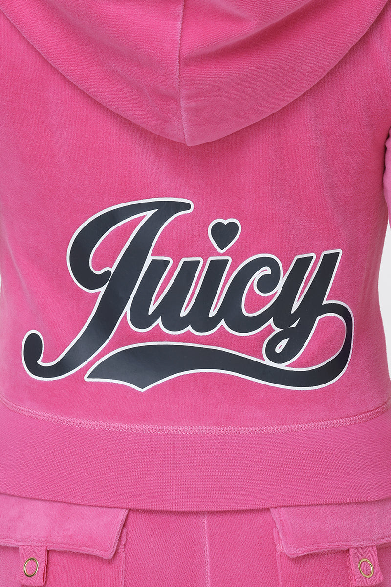 Wearing the Cotton Velour Hoodie, featuring a pink shade and the signature script "Juicy" logo in bold black and white lettering across the back, complete with a small heart above the “i” for a playful flair.