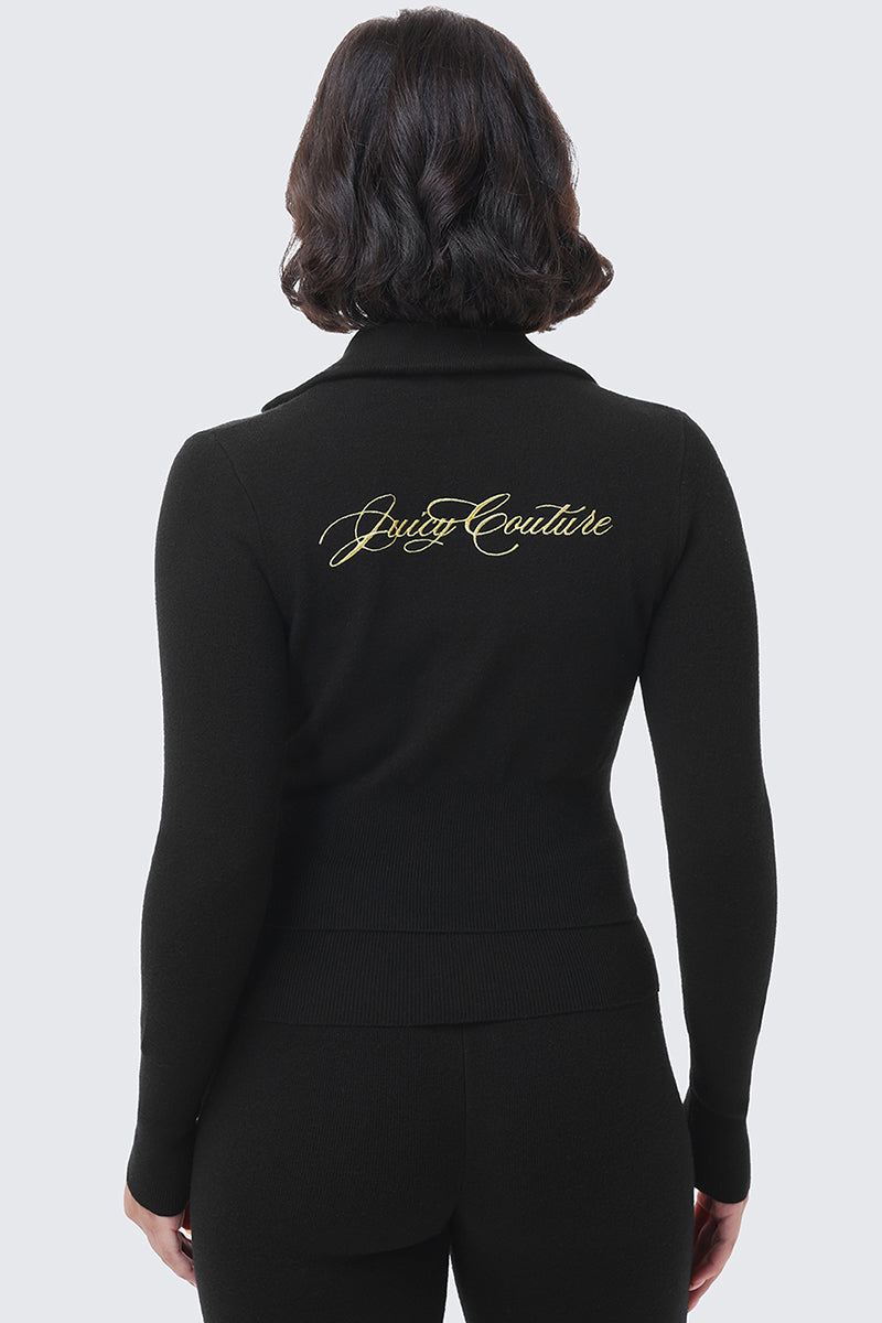 Back view of a person wearing a black long-sleeved Embroidered Knit Cropped Jacket featuring the Juicy Couture brand name embroidered in gold script across the upper back.