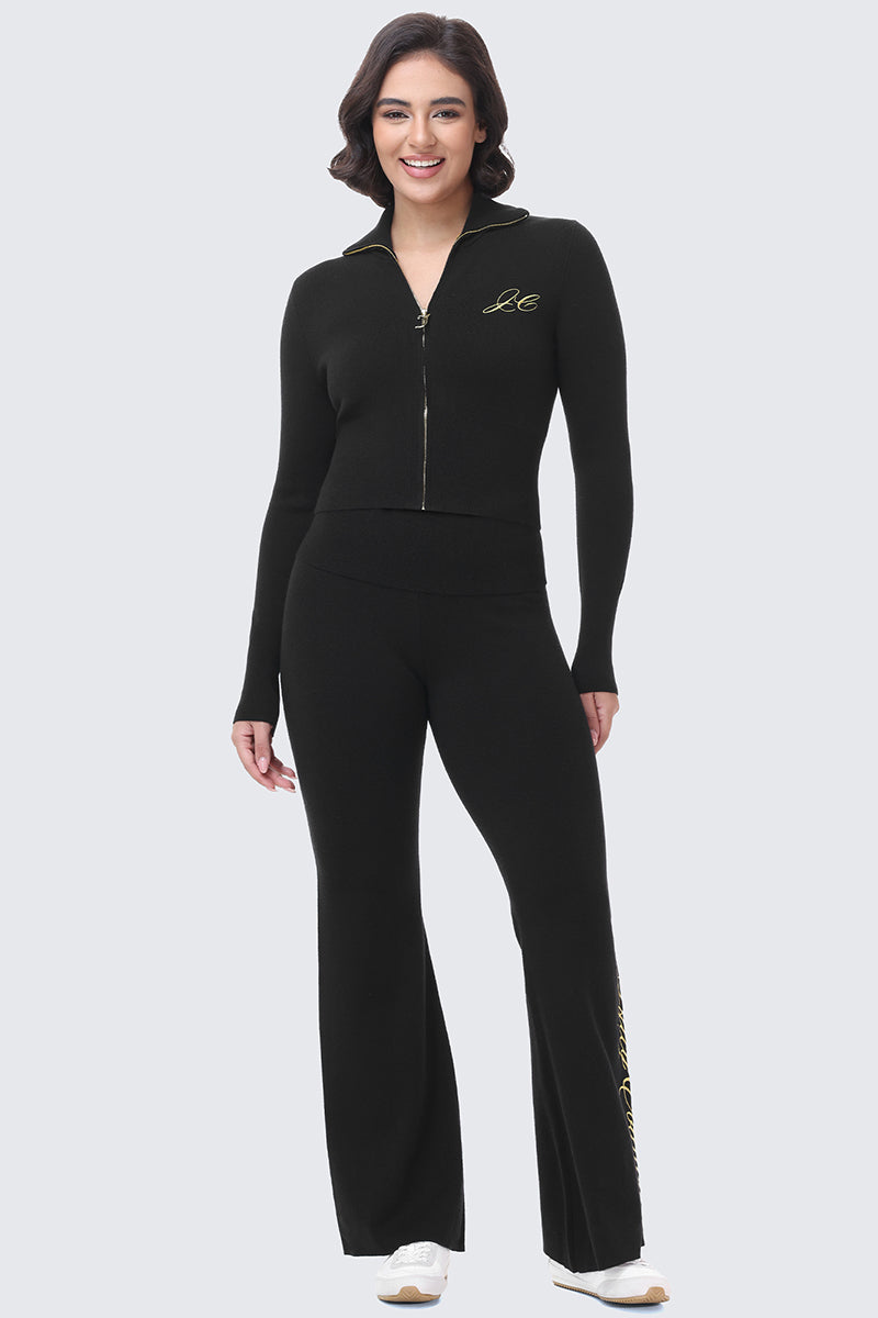 A woman wearing a black Juicy Couture zip-up knit jacket with an embroidered logo and matching Embroidered Knit Flare Pants.