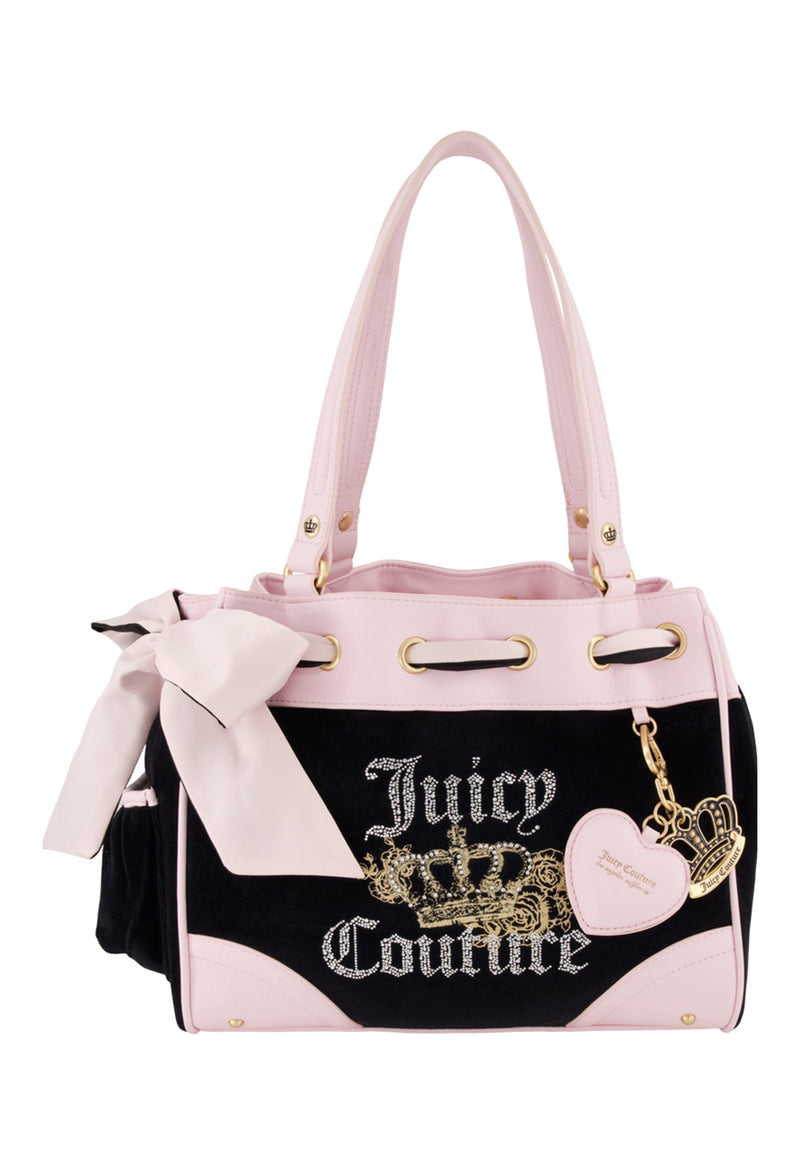 The Royal Bloom Daydreamer Tote Bag features a black and light pink design with gold accents, a bow on one handle, a heart-shaped charm, the Juicy Couture logo, and a gold crown detail on the front.