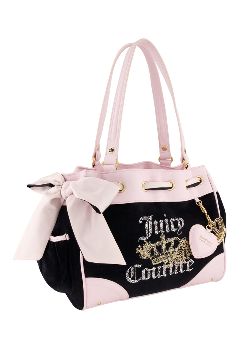The Royal Bloom Daydreamer Tote Bag by Juicy Couture features a black and light pink design, large front bow, gold embroidered logo with crown, heart-shaped pink keychain on the handle, and a spacious tote for signature Juicy style.