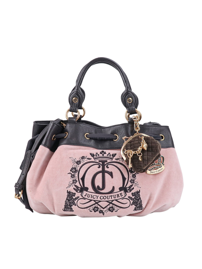 Pink Crowns & Kisses satchel bag with black trim, featuring a decorative floral crown logo on the front and a heart-shaped charm hanging from the handle.