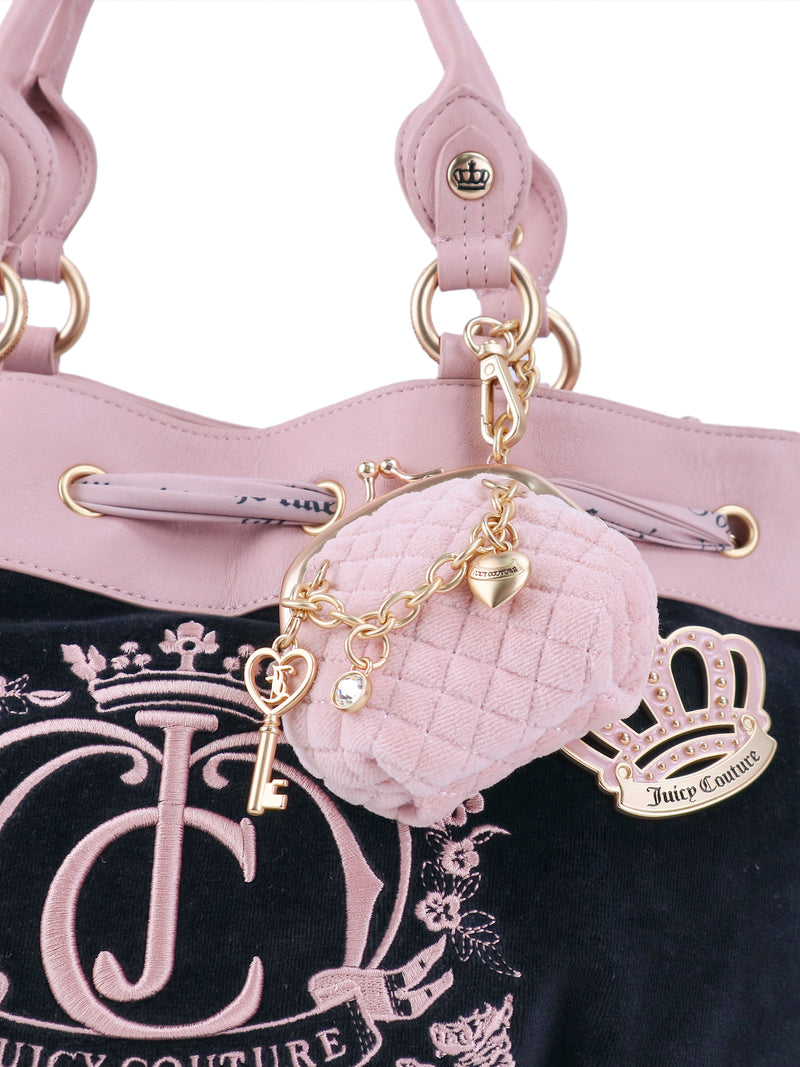 Black Crowns & Kisses Satchel with a pink embroidered crown and logo, featuring a detachable miniature pink coin purse charm and a gold-tone key charm hanging from the handle in a statement-making silhouette.