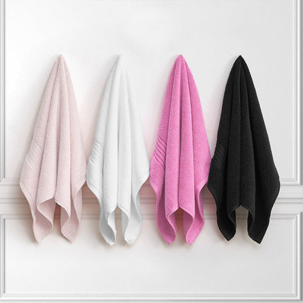Four towels in pink, white, black, and gray hanging against a white wall.
