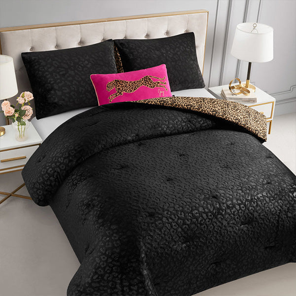 A black leopard-print bedding set styled on a bed, featuring a duvet cover, two matching pillow shams, and a vibrant hot pink accent pillow with a leopard-print cheetah design. The bed is set in a modern bedroom with a tufted headboard, bedside tables, lamps, and flowers.