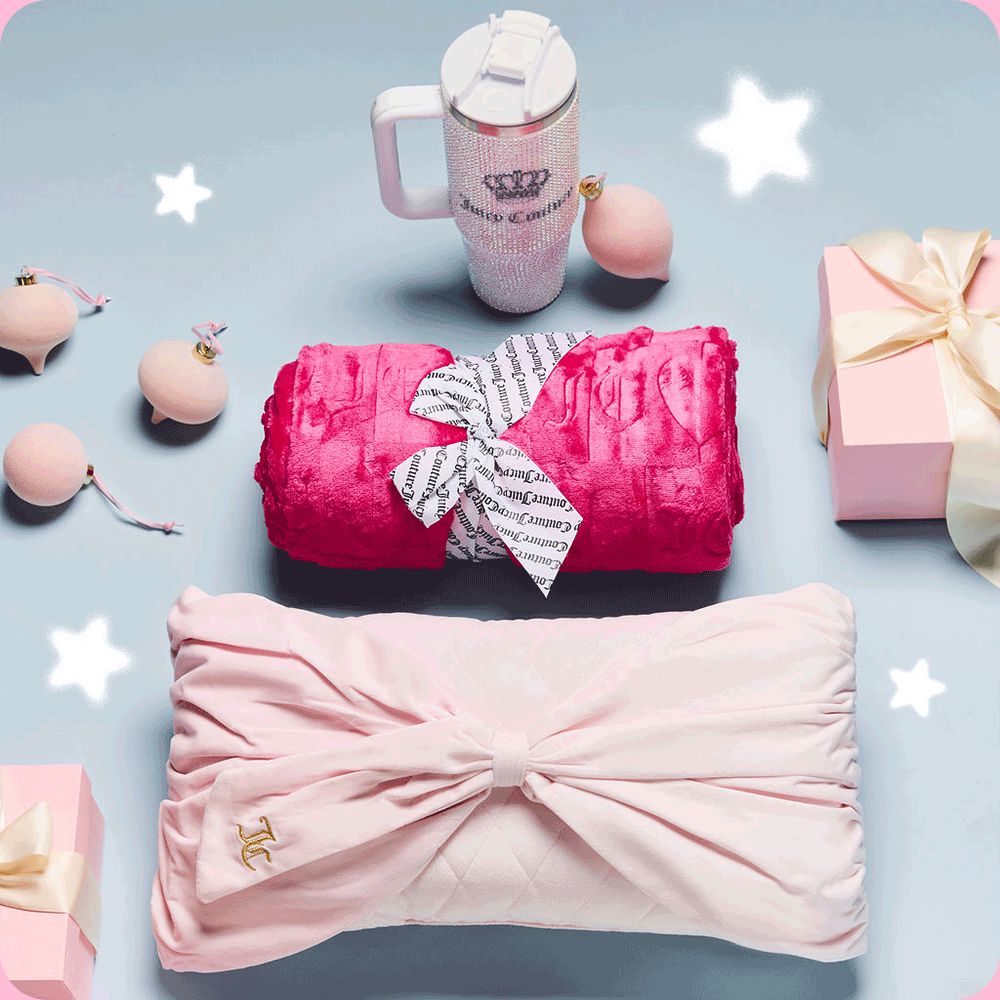 GIF of flatlay image of a hot pink blanket bundle, pink bowtie pillow, and a bedazzled white Juicy Couture tumbler with pink gift boxes and ornaments and white stars rotating above.