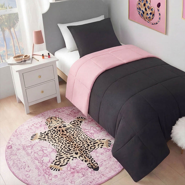 Bedroom with pink and black bedding, leopard print rug, and nightstand.