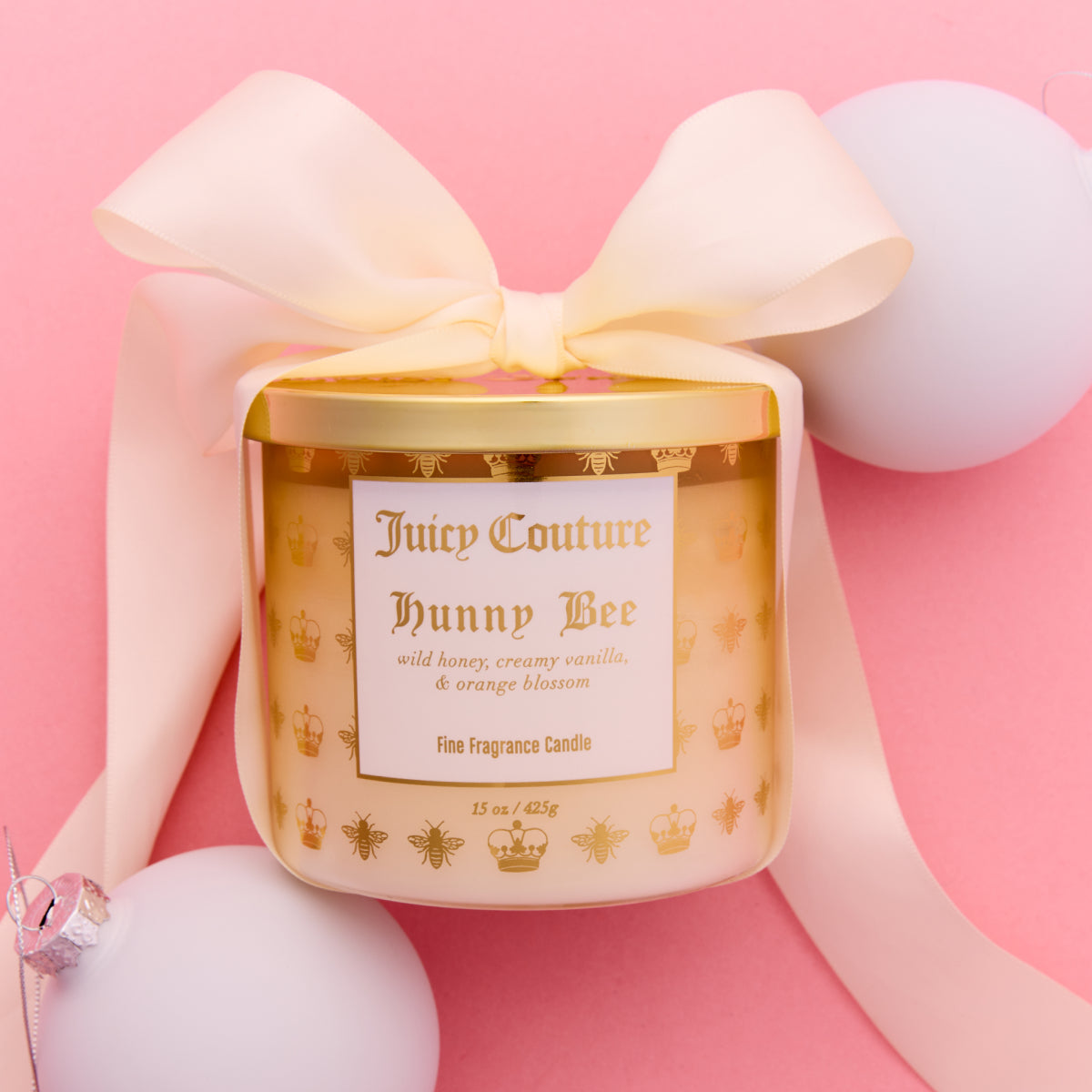 Juicy Couture Hunny Bee candle with a bow on a pink background