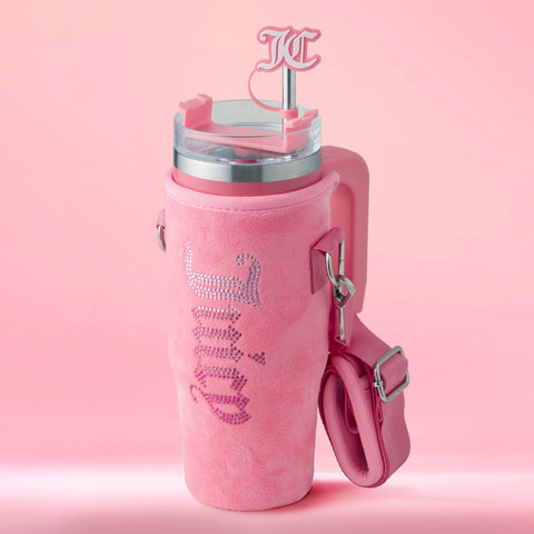 The Jetsetter Hydration Stainless Steel Tumbler with Neoprene Crossbody Pouch features a pink handle, KC-initial straw topper, fuzzy rhinestone-pink sleeve, and matching strap, all showcased against a solid pink backdrop.