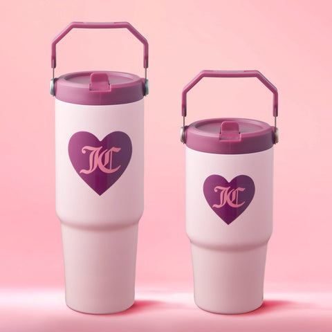 Two white Flip Flow Hydration Stainless Steel Tumbler Cups with purple lids and handles rest on a pink background. Each features a purple heart with "KC" inside. The set includes two sizes, ideal as a mommy and me 2-pack gift.
