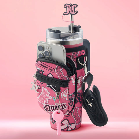 A pink-patterned Jetsetter Hydration Stainless Steel Tumbler sits inside a neoprene crossbody pouch with zippered pockets, holding a phone, keys with pink pepper spray, and a black case—topped with pink KC décor against a chic pink background.