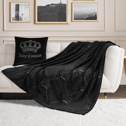 A white sofa with a black Juicy Couture pillow and the Embossed Plush Throw Blanket sits in a modern living room featuring framed art on the wall and a white rug on the floor.