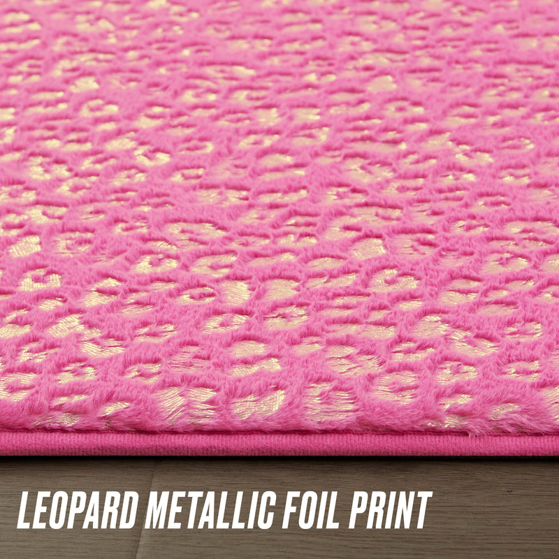 Close-up of the Metallic Leopard Plush Rug, 2' x 6', in hot pink with a shiny gold leopard print on a wooden floor. "LEOPARD METALLIC FOIL PRINT" appears at the bottom in bold white letters.
