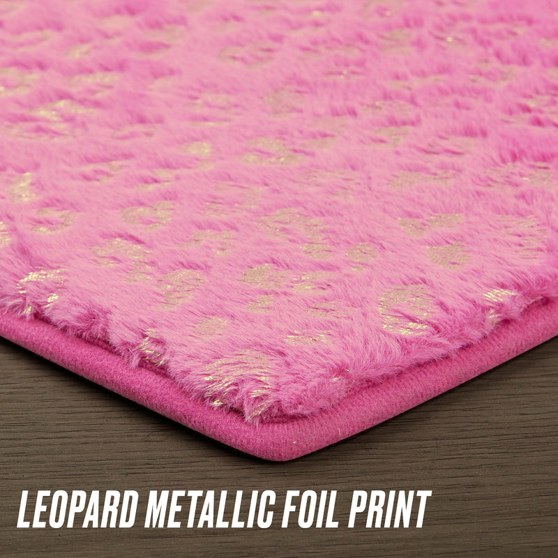 A close-up of the Metallic Leopard Plush Rug, 3' Heart, featuring pink glam plush with metallic gold leopard print on a dark wood background. "Leopard Metallic Foil Print" appears at the bottom, evoking chic Juicy Couture style.