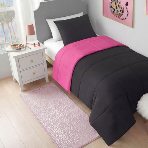 A neatly made bed with black and bright pink bedding sits by a white nightstand holding a lamp and makeup. The Metallic Leopard Plush Rug, 2' x 6', and metallic foil leopard print wall art add flair to this bright, modern room.