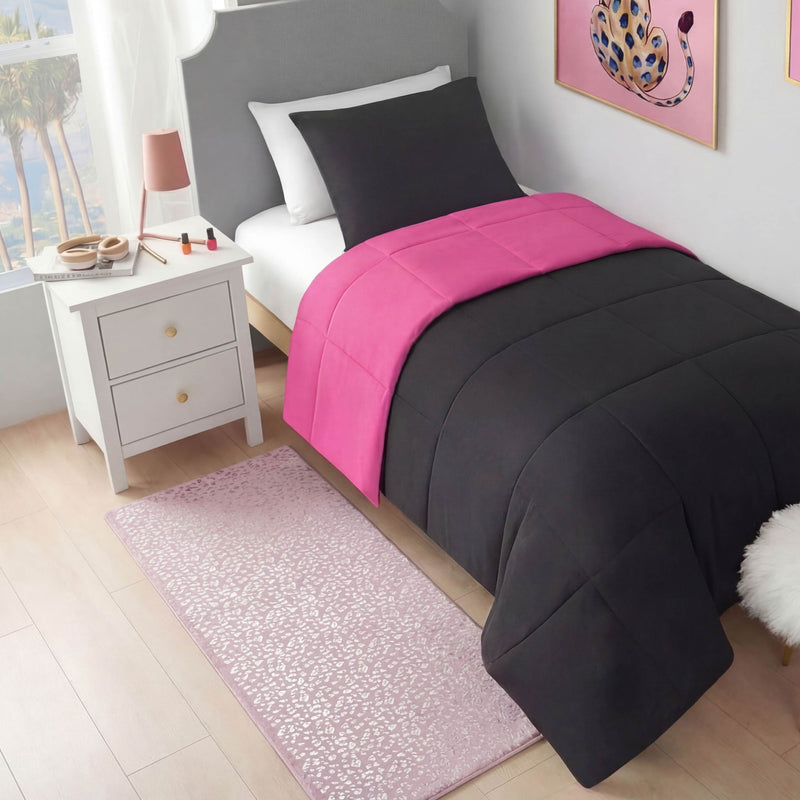 A neatly made bed with black and bright pink bedding sits by a white nightstand holding a lamp and makeup. The Metallic Leopard Plush Rug, 2' x 6', and metallic foil leopard print wall art add flair to this bright, modern room.