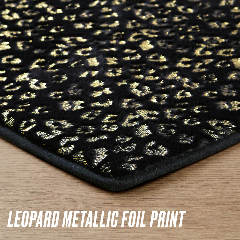 Close-up of the Metallic Leopard Plush Rug, 3' Heart, in black with a shiny gold leopard metallic foil print. The rug’s lower edge rests on a light wood floor with "LEOPARD METALLIC FOIL PRINT" at the bottom.