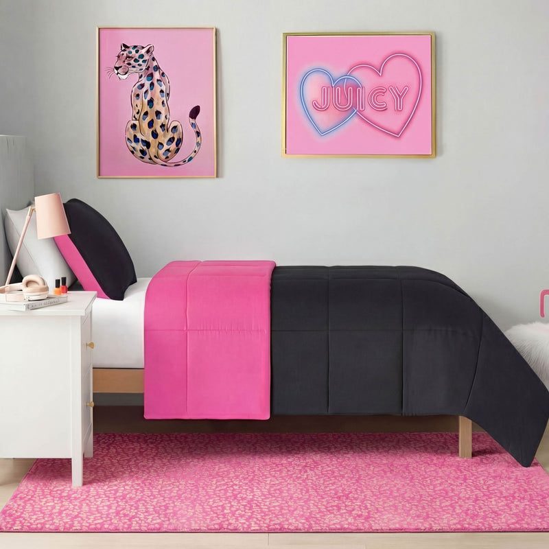 A neatly made twin bed with black and hot pink bedding sits against a gray wall, beneath two framed prints: a pink leopard illustration and a neon pink Juicy sign. A Metallic Leopard Plush Rug, 4' x 6', covers the floor.