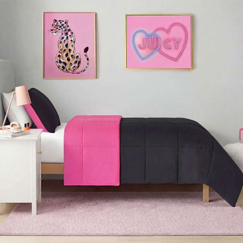 A neatly made bed with a black and bright pink comforter sits against a light gray wall. Above the bed, two framed artworks—a leopard print and one with pink hearts and "JUICY"—hang, while a Metallic Leopard Plush Rug (4' x 6') adds flair.