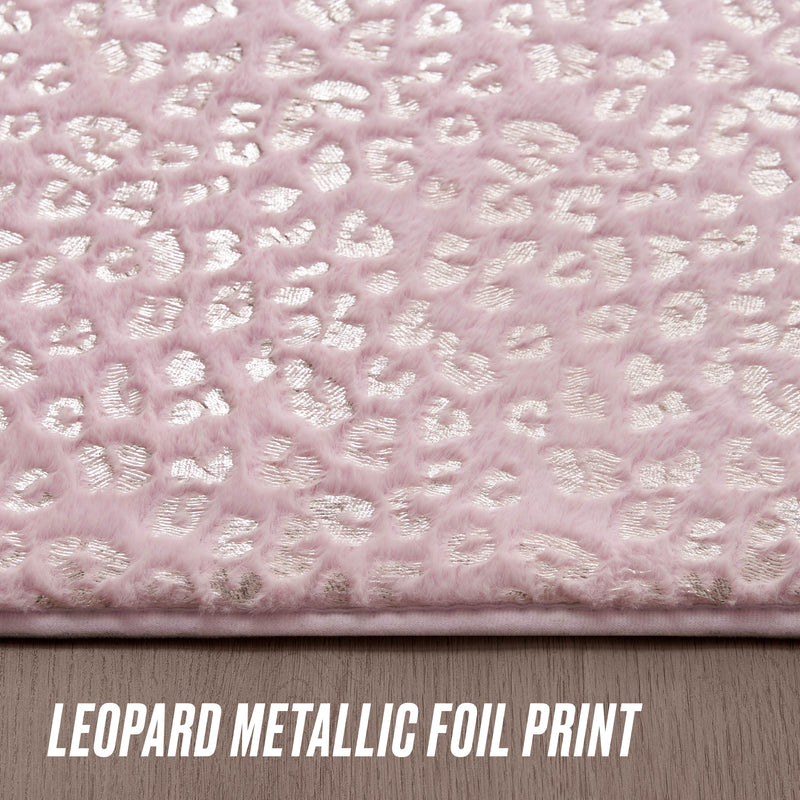 Close-up of the Metallic Leopard Plush Rug, 4' x 6', featuring soft pink fabric with a metallic silver leopard print pattern. The text "LEOPARD METALLIC FOIL PRINT" appears at the bottom. The rug is shown on a wooden surface.