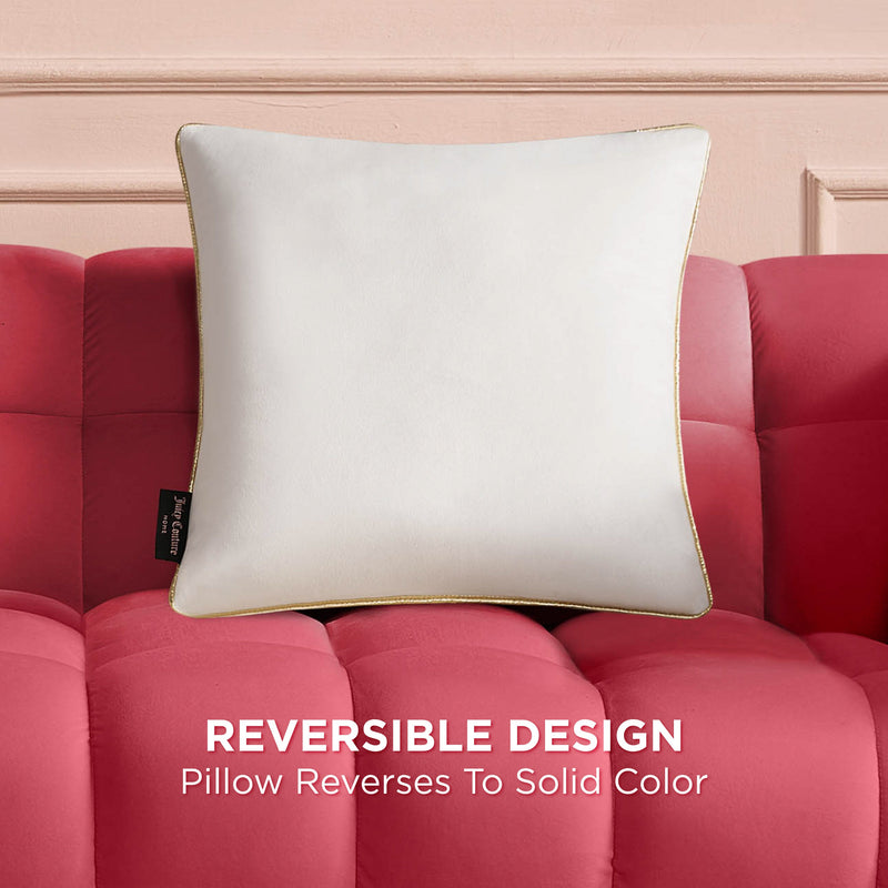 The Velvet Cheetah Pillow with gold piping rests on a red tufted sofa. A black side tag is visible. Text below reads: Reversible Design—this decorative pillow reverses to a solid color.