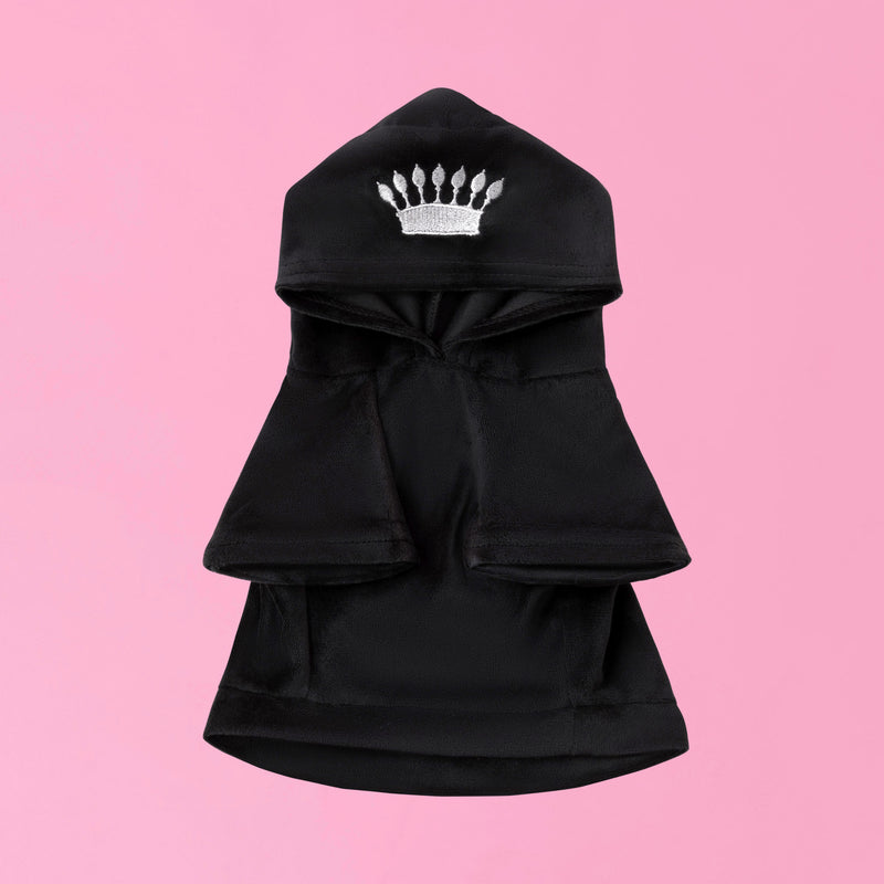 The Bling Velour Pet Hoodie, featuring a black design with a silver crown emblem on the hood and reminiscent of a Juicy Couture pet hoodie, is displayed on a pink background.