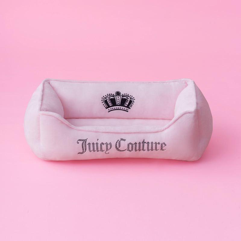 A black velour pet bed with Juicy Couture and a crown logo embroidered on the front, featuring subtle bling accents and set against a black background.