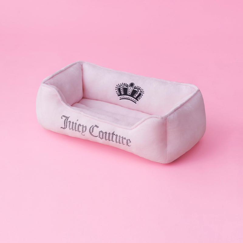 A black Crown Bling pet bed from Juicy Couture, featuring a sparkling crown design and brand name on the front with subtle bling accents, set against a solid pink background.