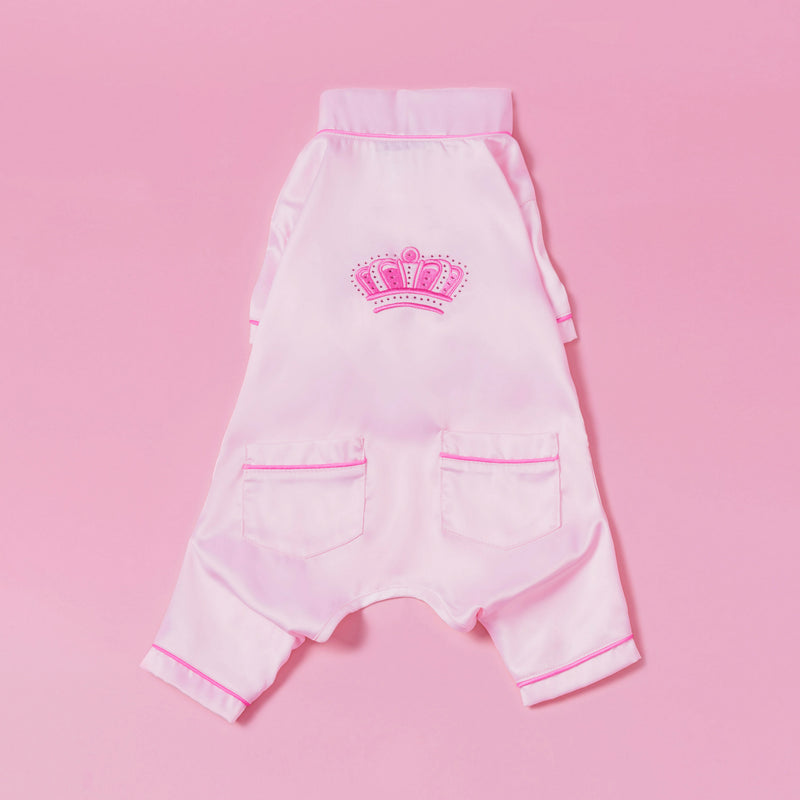 Juicy Couture Pet Silky Satin Pajamas in light pink, featuring two back pockets, pink trim, and a crown design on the back, displayed on a solid pink background.