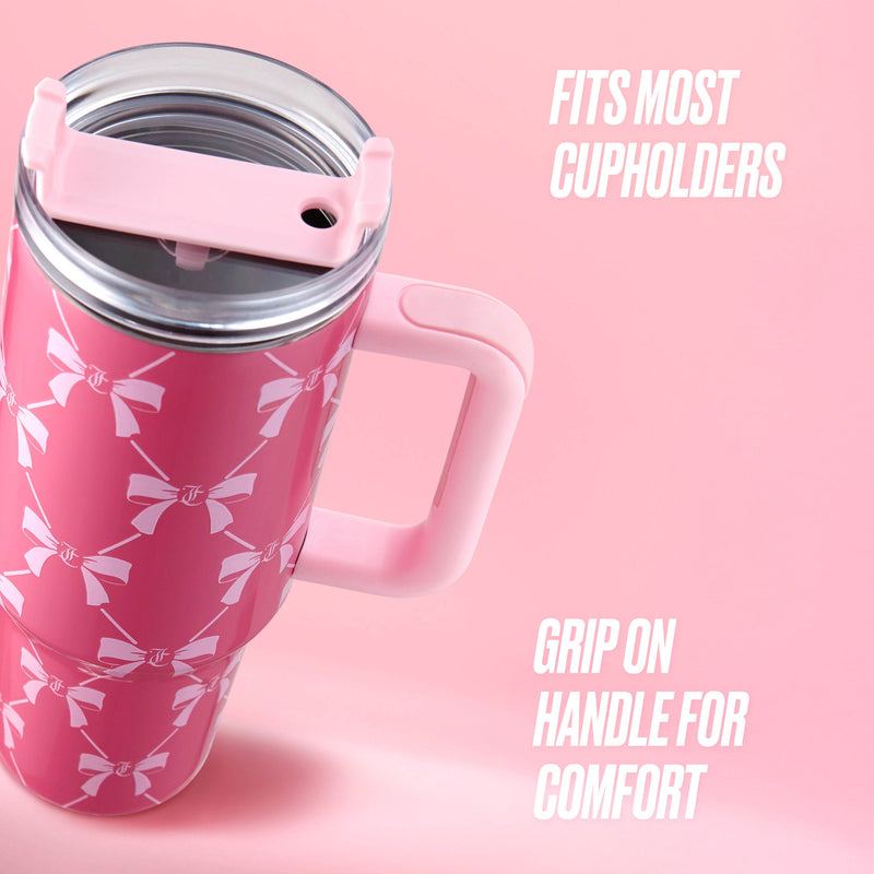 The Jetsetter Hydration Stainless Steel Tumbler, 40 oz, in pink with white bow patterns and a handle, is shown against a pink background. Text: Fits most cupholders. Handle provides a comfortable grip.