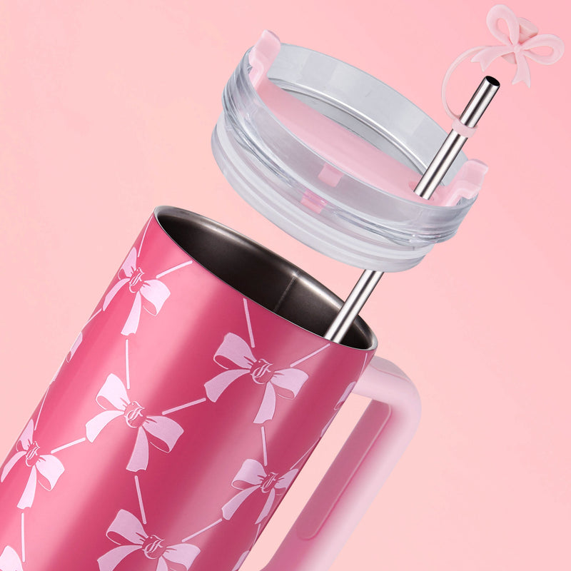 The Jetsetter Hydration Stainless Steel Tumbler, 40 oz, in pink with a handle and white bow designs, sits on a pink background. Its lid and metal straw with a pink bow hover just above the tumbler.