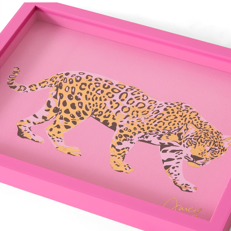 A 12″ x 16″ Shadow Box Wall Art features an illustrated leopard with yellow, black, and lavender spots set against a pink background. Inspired by fashion-inspired artwork, this piece includes a border and a signature in the lower right corner.