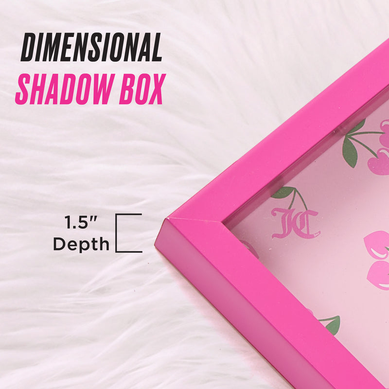 A pink Shadow Box Wall Art, measuring 12″ x 16″ with a 1.5-inch depth, is displayed on a white fur background, channeling fashion-inspired decor. The box showcases an eye-catching floral and cherry motif reminiscent of Juicy Couture shadow box styles. Text on the image reads: DIMENSIONAL SHADOW BOX and 1.5 Depth.