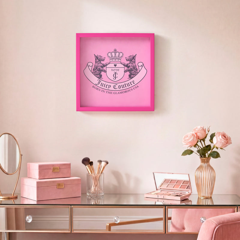 A vanity table with makeup, a vase of pink roses, pink storage boxes, and a 14″ x 14″ Shadow Box Wall Art on a light-colored wall.