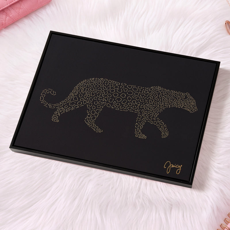 A black rectangular Shadow Box Wall Art (16″ x 20″) features a golden leopard silhouette formed from small dots, set against a white furry surface. Fashion-forward and luxurious, the artwork is signed “Juicy” in gold at the bottom right—making it an ideal piece of Juicy Couture wall art for any stylish space.